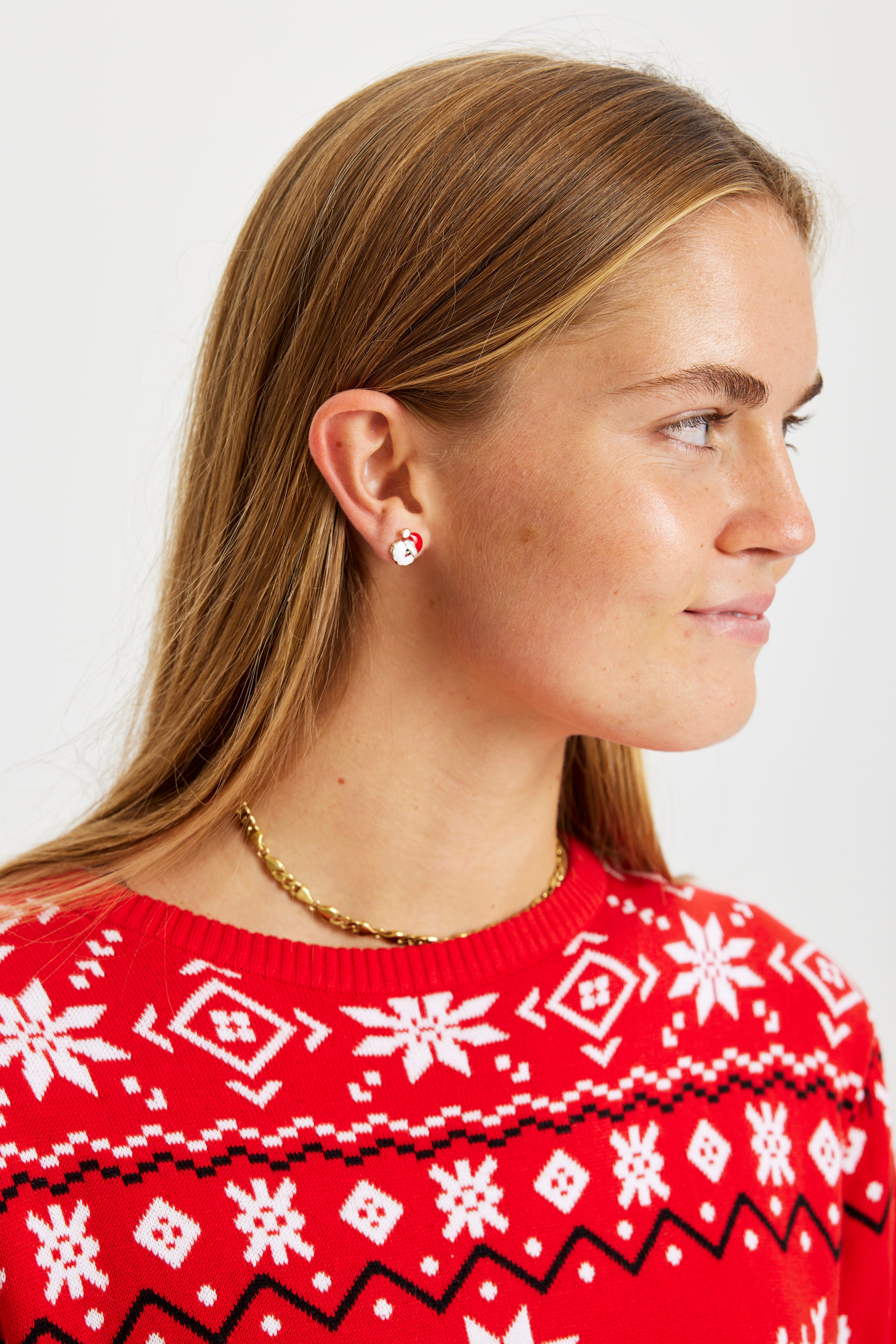 Eine Frau trägt Weihnachtsohrringe, die wie der Weihnachtsmann aussehen.